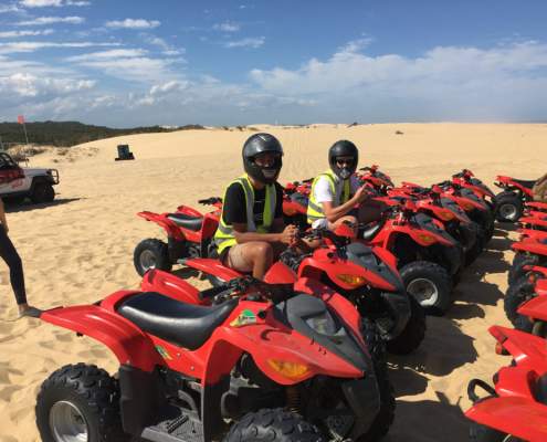 Red quad bikes lined up on sand dune