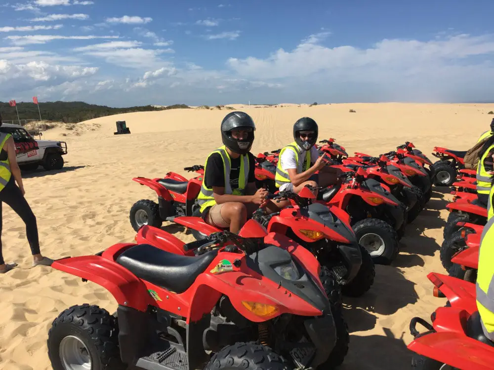 Red quad bikes lined up on sand dune